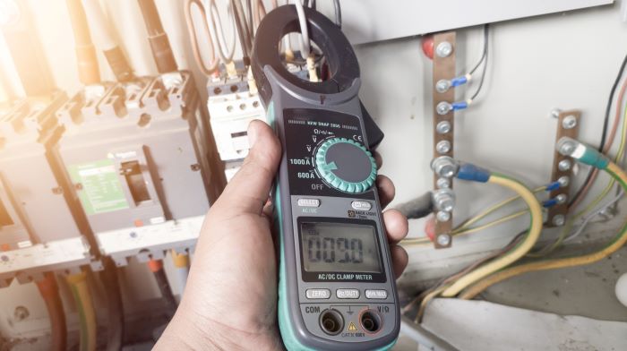 electricians hand holding multi meter testing current
